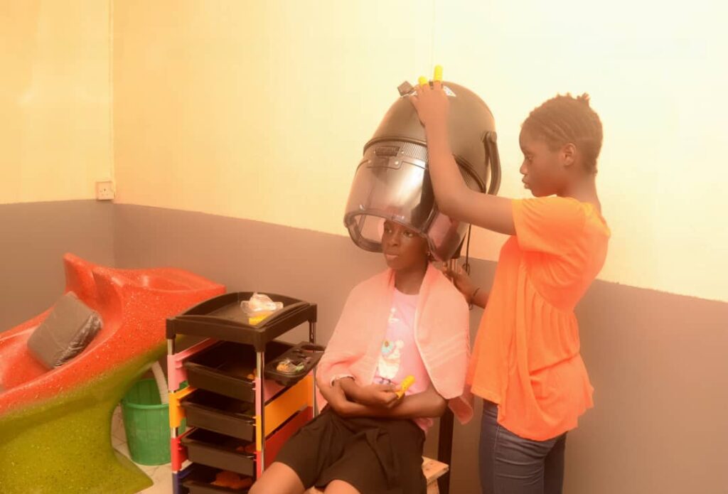 Hair Dressing section: one of our beneficiaries setting hair for another beneficiary in a practical class.